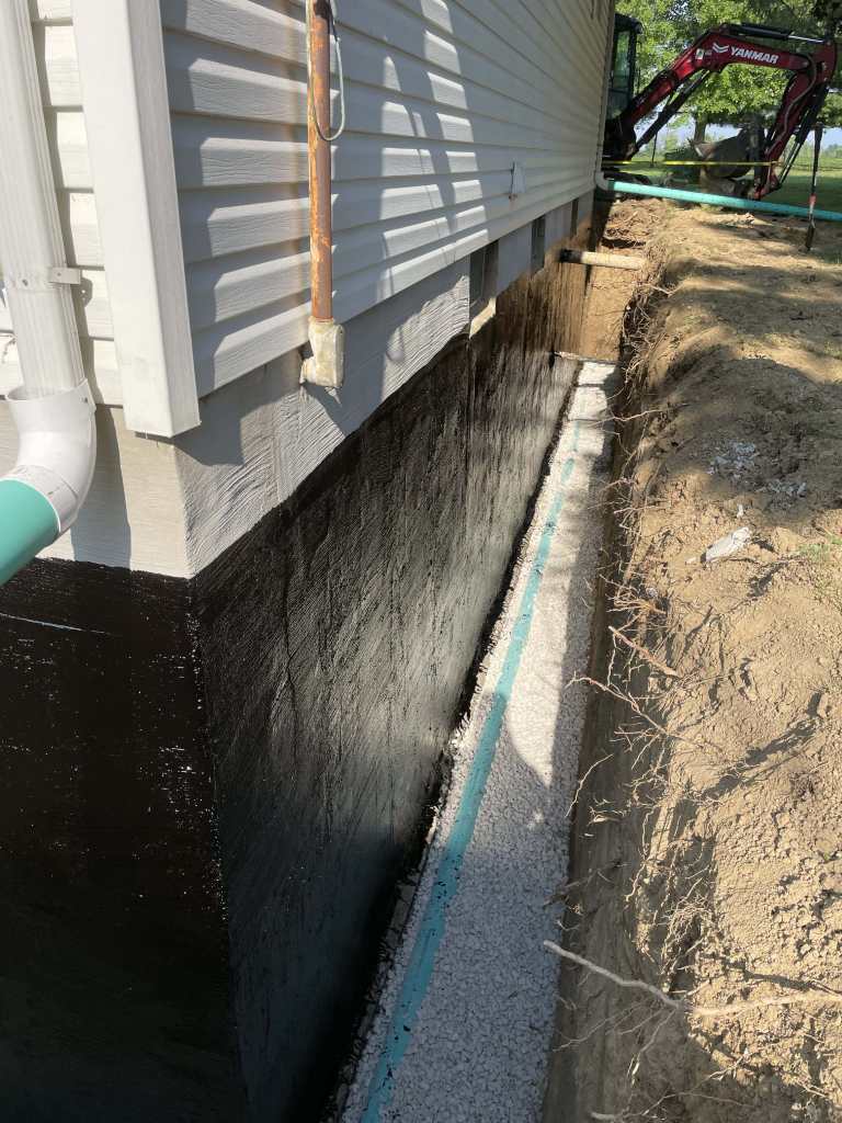 Excavated foundation with waterproofing applied.