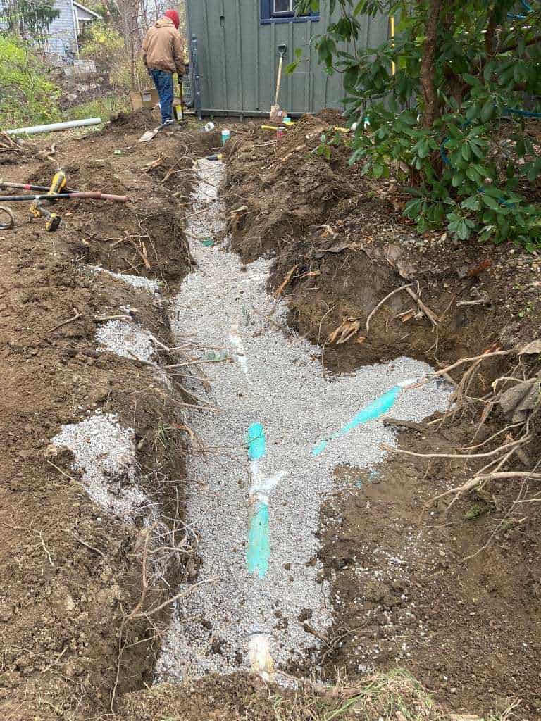 Excavated trench with pipes and gravel.