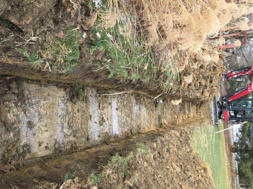 Excavated trench in grassy area
