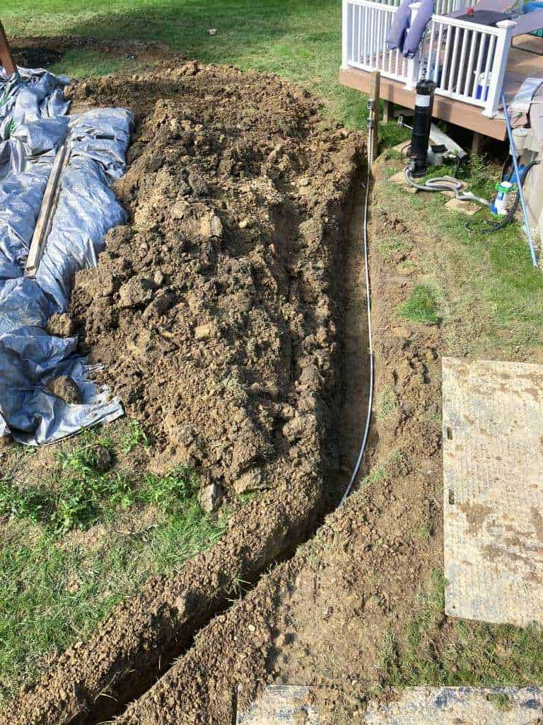 Excavated trench in grassy area.