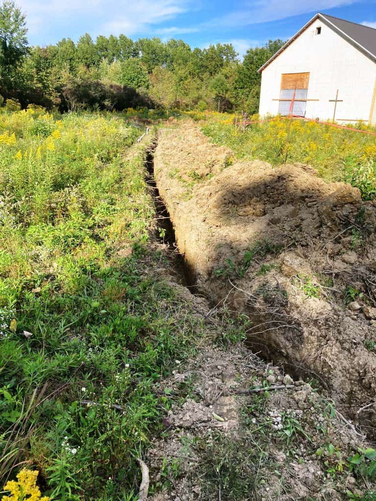 Trench in overgrown field near building